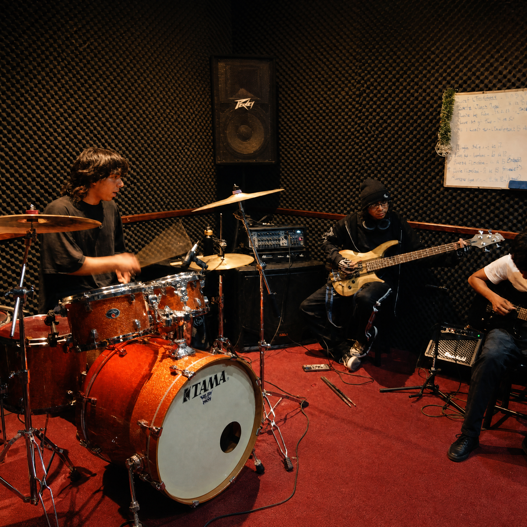 Ensayo de estudiantes con batería, bajos y guitarras